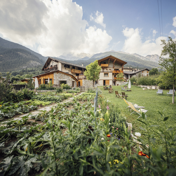 Locanda Mistral, a family-run Occitan-style hotel with a stone facade, organic garden and lawn with sun loungers, set against the mountains of Valle Maira in Piedmont
