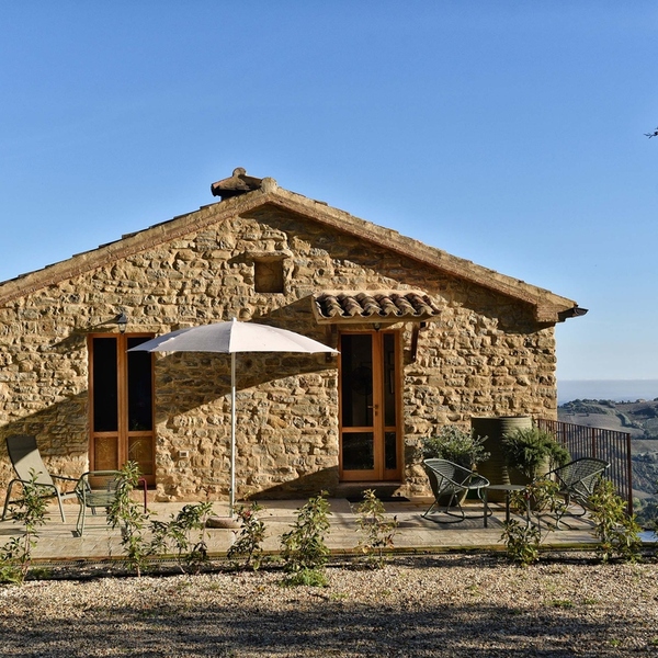 Refugium Hideaways holiday home, a restored stone cottage with a terrace and parasol overlooking the rolling hills of Le Marche in Italy